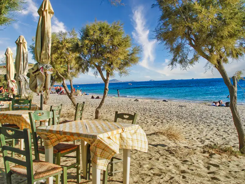 Taverna tables under tamarisk trees on Agia Anna beach in Naxos