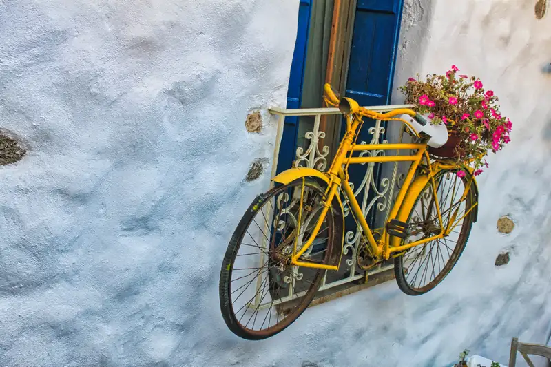 Old yellow bicycle and flowers on a whitewashed wall in Naxos Town