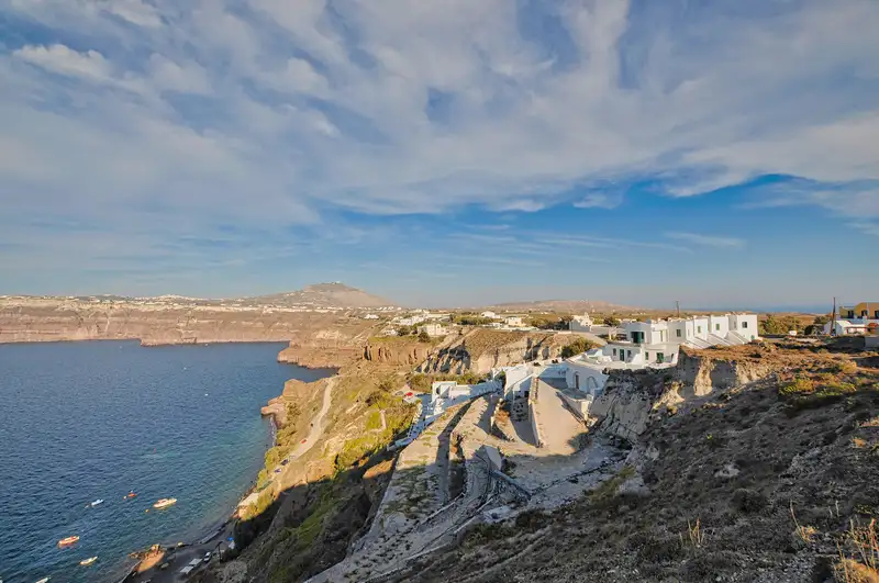 Whitewashed houses of Akrotiri above the caldera in Santorini, with steps leading to a small cove