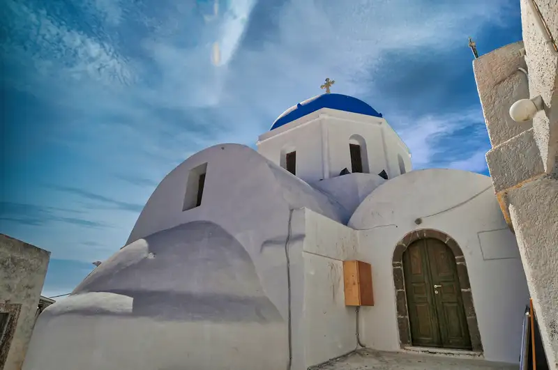 A whitewashed church with a blue dome in Pyrgos, Santorini