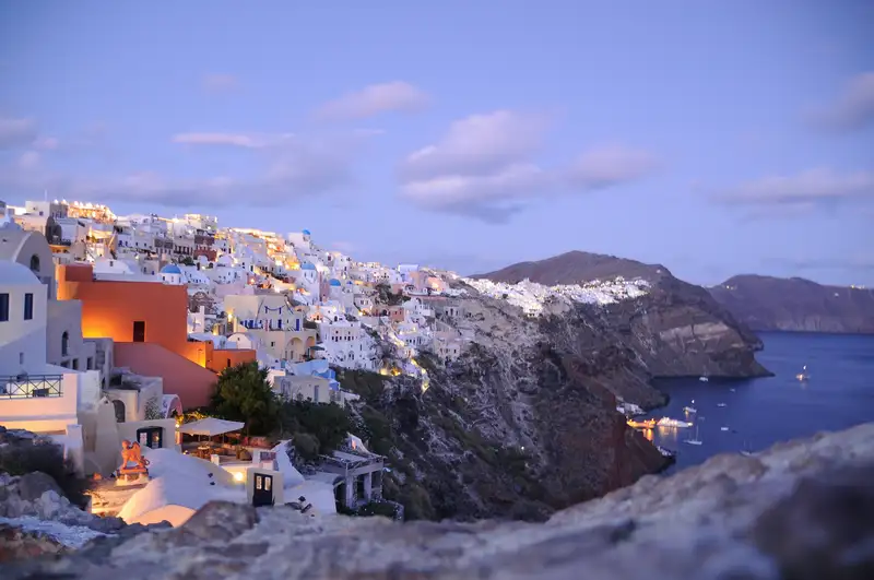 The village of Oia in Santorini cascading down the cliff at dusk with lit houses