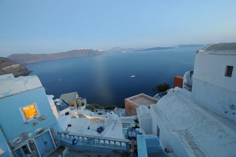 View over the Santorini caldera from Oia at dusk, framed by whitewashed houses