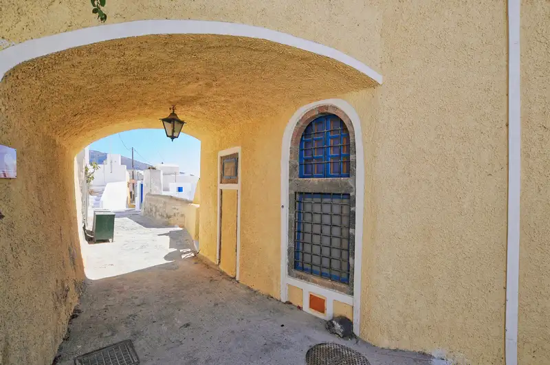 Covered alley with a lantern leading into the whitewashed lanes of Pyrgos, Santorini