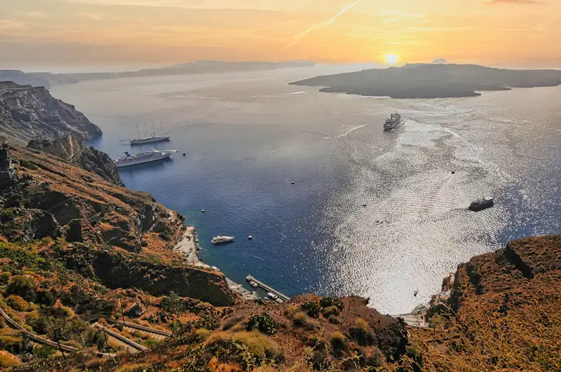 Sunset over the Santorini caldera with ships on the water seen from the Fira cliffs