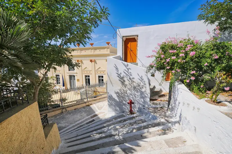 Stone steps climbing past a neoclassical mansion and bougainvillea in Pyrgos, Santorini
