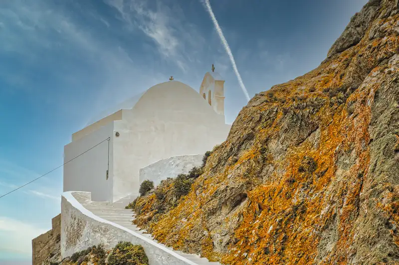 Whitewashed church with a blue door and bell tower in Chora, Serifos