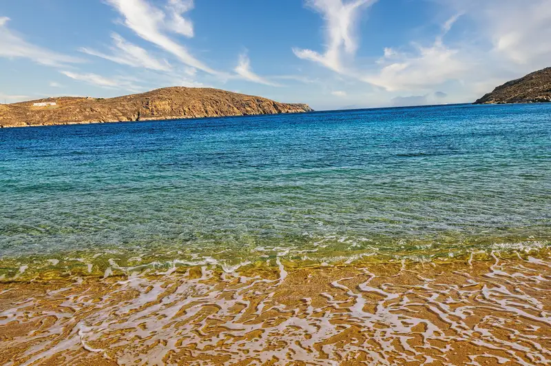 Crystal-clear shallow water meeting golden sand at Livadakia beach
