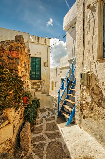 Narrow alley with stone steps and a blue staircase in Chora