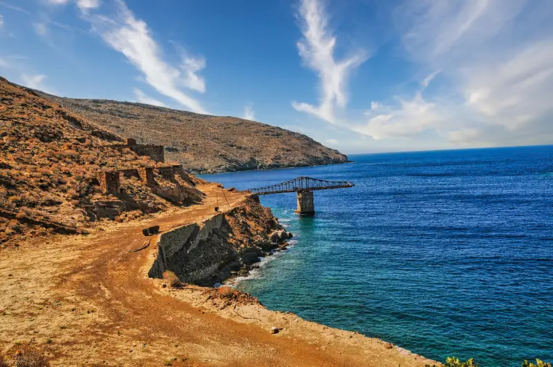 Rusted loading bridge of the old iron mine reaching into the sea at Megalo Livadi