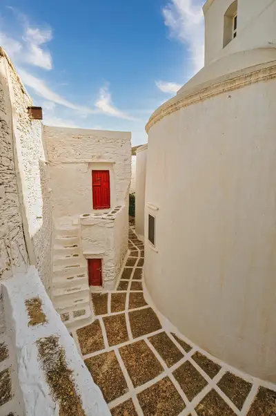 Narrow white passage with red doors beside the church at Taxiarches Monastery, Serifos
