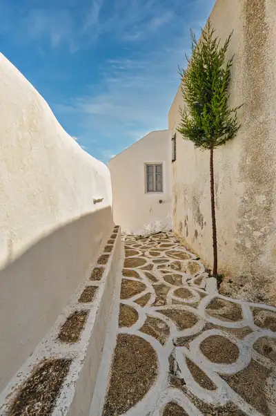A quiet cobbled lane between white walls in the village of Chora on Sikinos