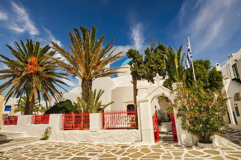 Whitewashed church and red gate in the central square of Chora on Sikinos