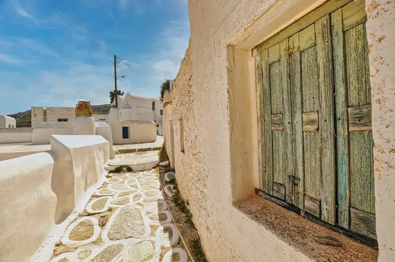 Old green window in a stone wall along an alley in Chora on Sikinos