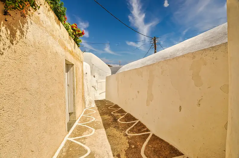 Narrow whitewashed lane with geraniums leading through Kastro Sikinos