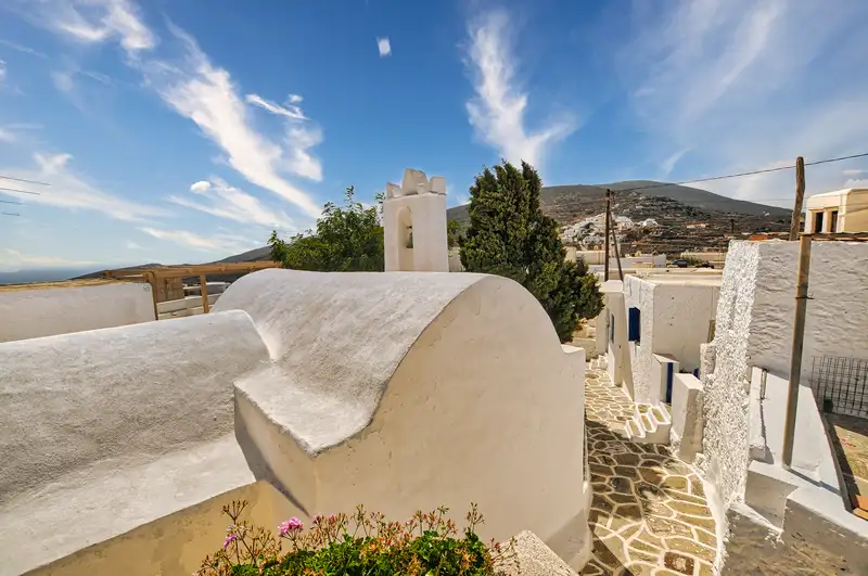 Small white church with a belfry on a lane in Kastro on Sikinos island