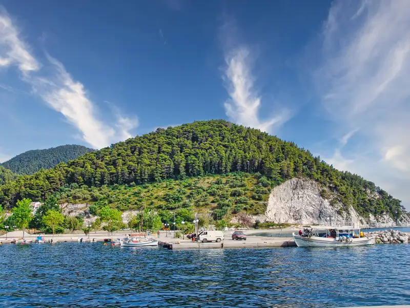 A green forested hill above a quiet harbour at Klima, Skopelos