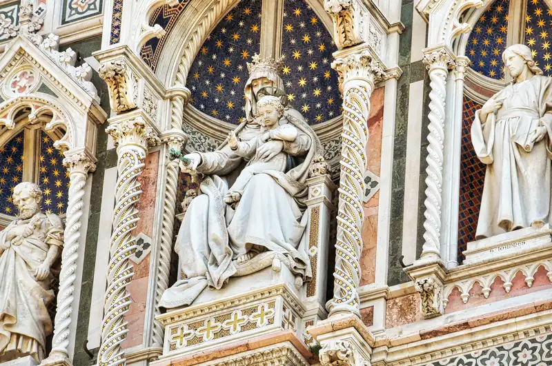 Marble Madonna and Child sculpture on the facade of Florence Cathedral set against a starry gold background