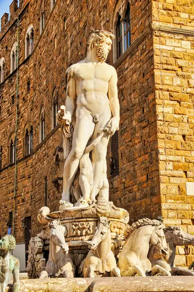 White marble Neptune of the Biancone fountain against the stone wall of Palazzo Vecchio in Florence