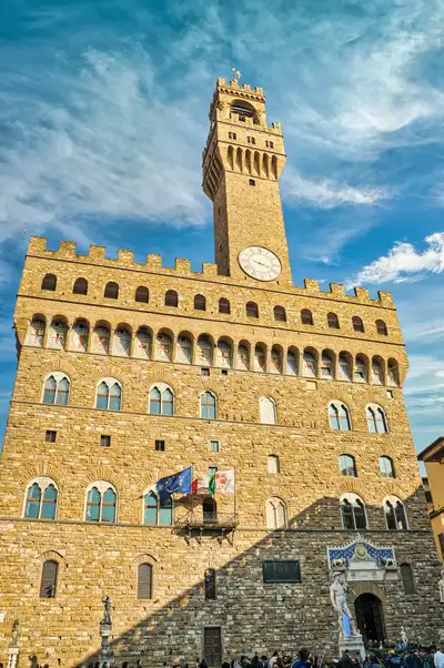 Palazzo Vecchio and its tall bell tower with flags in Piazza della Signoria, Florence