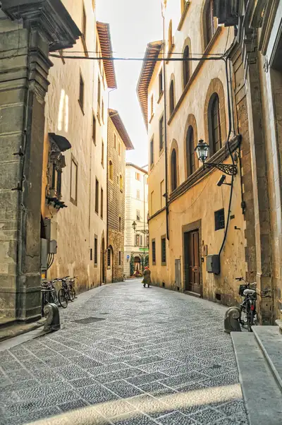 Narrow cobblestone street lined with old buildings and parked bicycles in Florence