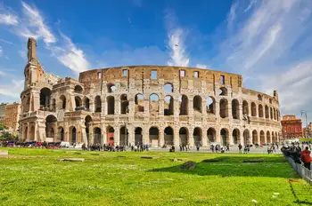 The ancient Colosseum amphitheater rising above green lawns in Rome, Italy