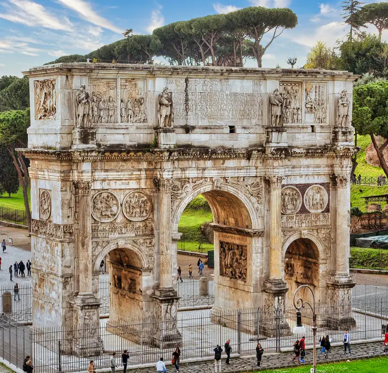 The Arch of Constantine in Rome, carved with reliefs beneath stone pines