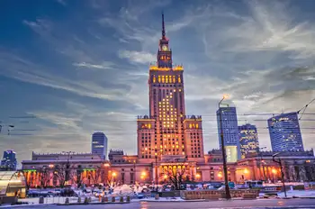 The illuminated Palace of Culture and Science towering over the Warsaw skyline at dusk