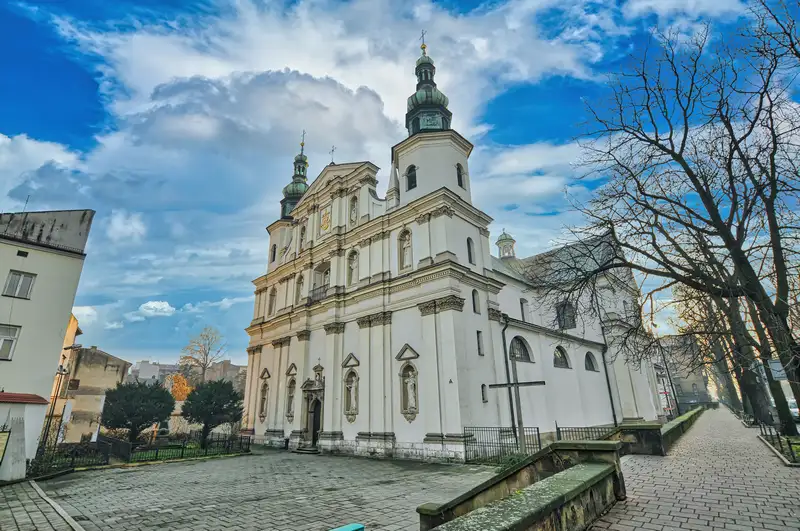 Historic church facade with green cupolas and stone statues in Krakow, Poland