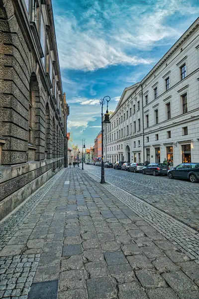 Historic stone buildings along a quiet cobbled street in Poznan