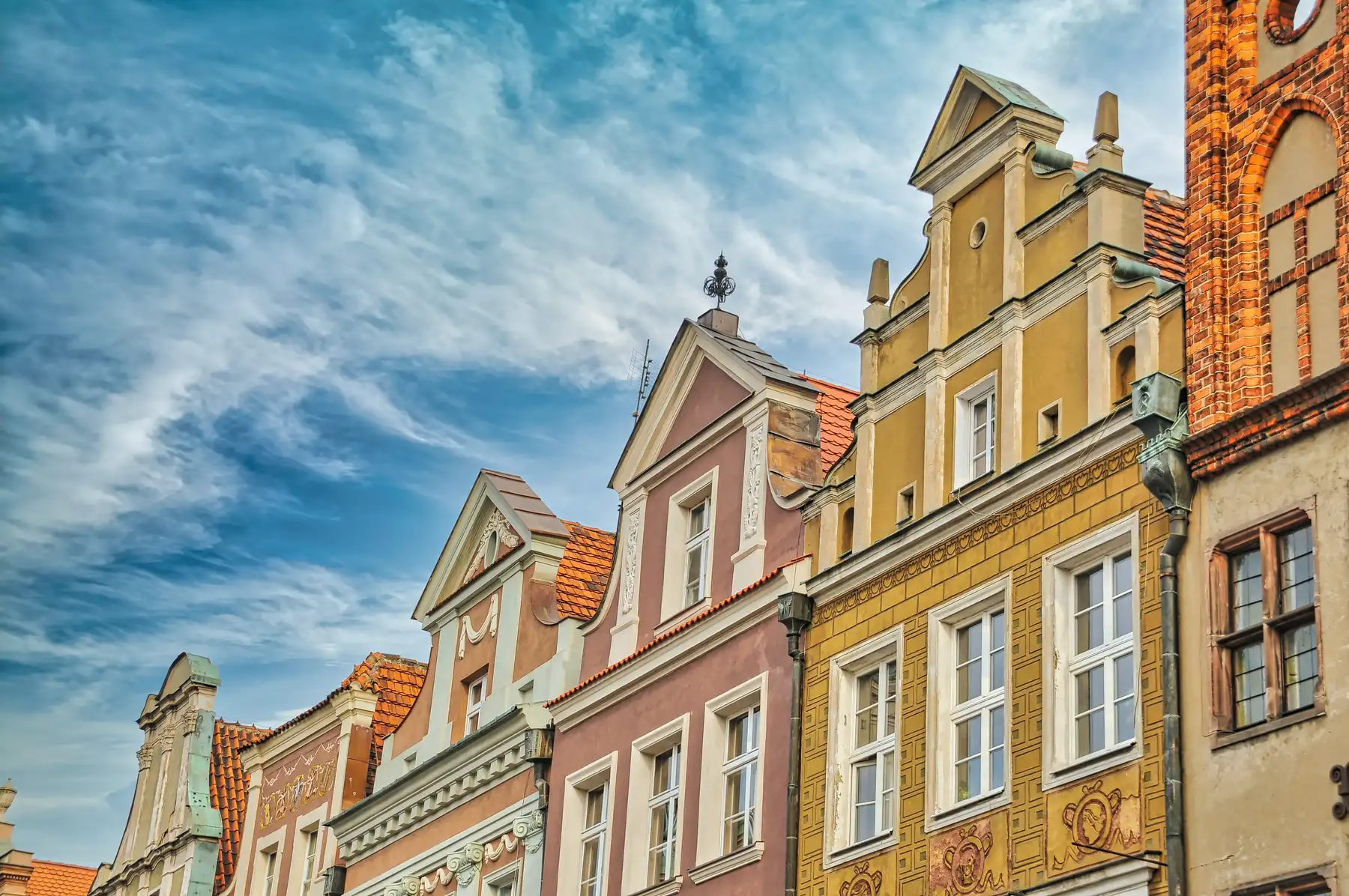 Row of townhouse rooftops and painted facades in Poznan