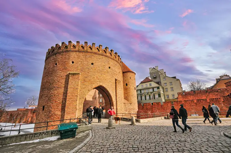 People walking through the brick gate of the Warsaw Barbican