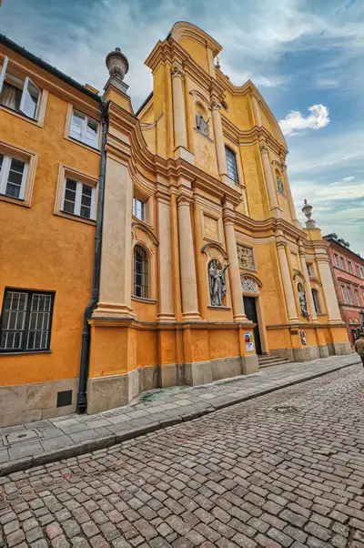 Ochre baroque church facade on a cobbled street in Warsaw Old Town